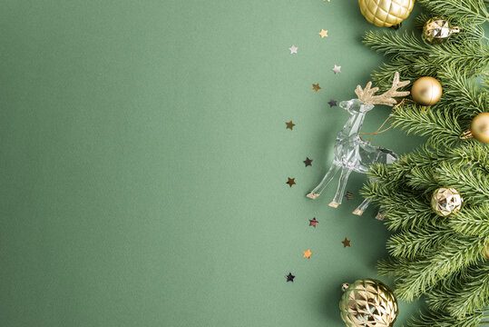 Christmas holiday decorative arrangement with reindeer and golden ornaments on green background