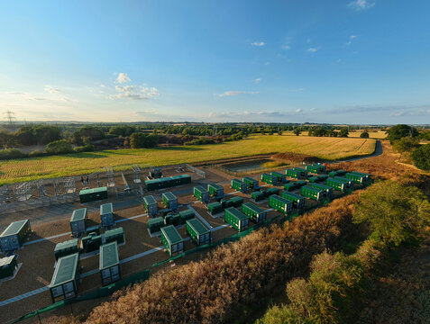 Aerial view of Battery Energy park, BESS Grendon, featuring rows of green battery storage containers in a rural landscape with fields in Northampton, England, United Kingdom.