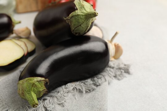 Fresh raw eggplants and other products on light grey table, closeup. Space for text