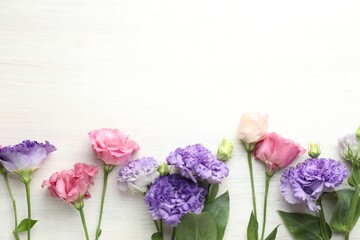 Obraz premium Beautiful eustoma flowers on white wooden table, flat lay. Space for text