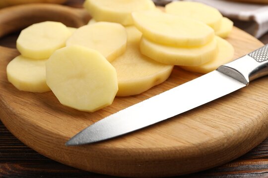 Pieces of fresh raw potatoes and knife on cutting board, closeup