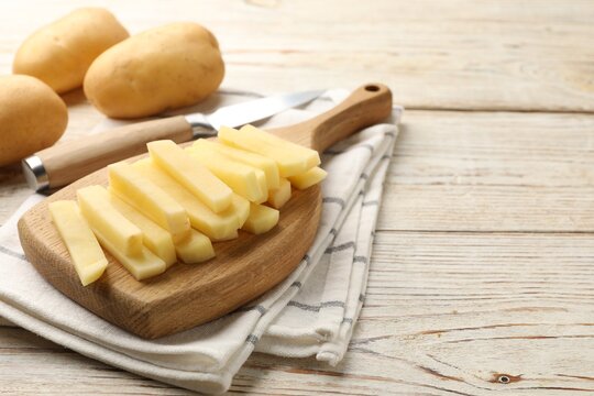 Fresh raw potatoes and knife on wooden table, closeup. Space for text