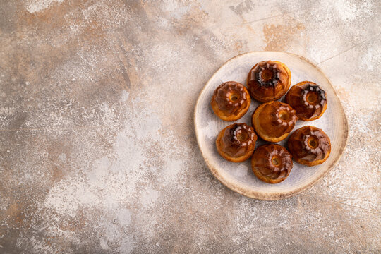 Golden caramelized Canele on brown concrete, copy space, top view