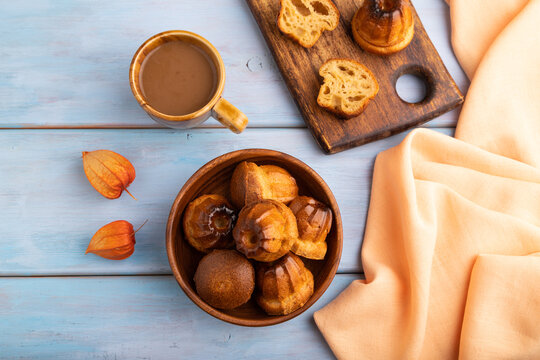 Golden caramelized Canele on blue wooden, close up, top view