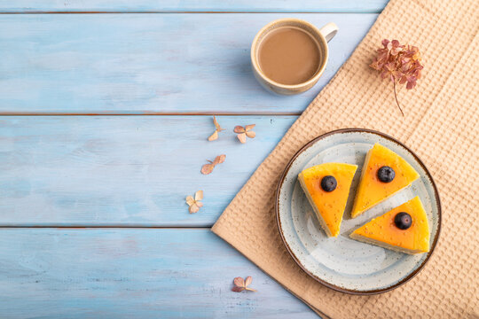 Cheesecake with mango cream on blue wooden, copy space, top view