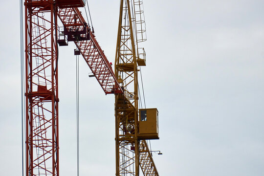 Intersection of Red and Yellow Tower Crane Jibs on Active Construction Site
