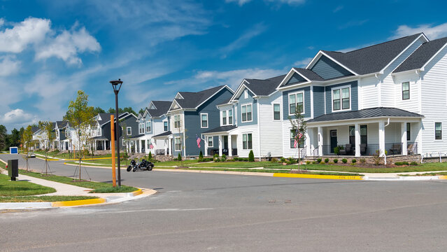 Corner view shows modern detached houses around a residential intersection in Leesburg, Virginia.