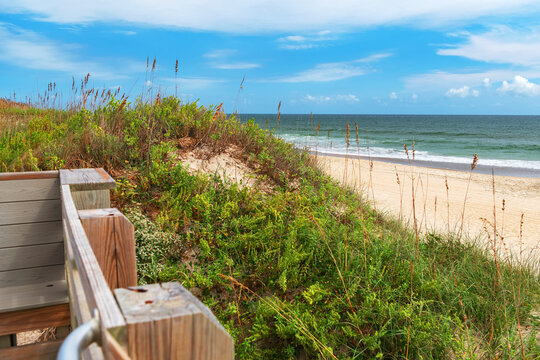 Wooden beach steps border a grassy dune overlooking the North Carolina shoreline.