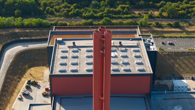 Aerial view of the Rookery South ERF facility featuring its prominent red chimney stack, flat roof with skylights, and surrounding industrial grounds in Stewartby, England, United Kingdom.