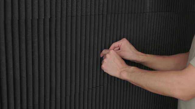 Soundproofing test on acoustic board. Evaluating sound insulation with acoustic panel testing. Technician assesses soundproofing effectiveness of acoustic panels in studio