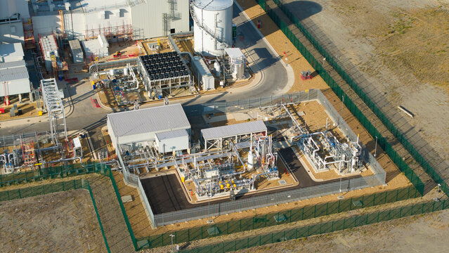 Aerial view of Millbrook Power Plant showing industrial infrastructure, complex piping systems, storage tanks, and fenced enclosures in Stewartby, England, United Kingdom.