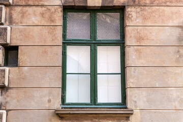 Obraz premium Rectangular wooden window with green frame in rusticated stone wall