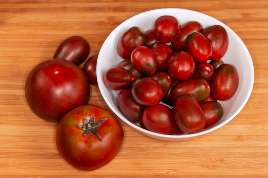 Reddish brown plum tomatoes, big round tomatoes on cutting board