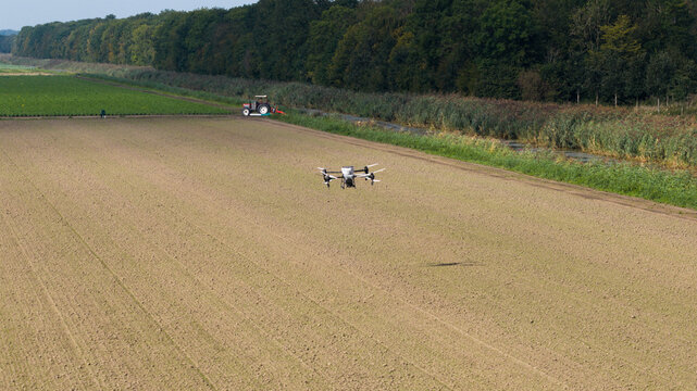 Aerial view of an agricultural UAV spraying and seeding crops, showcasing precision farming, automation, smart agriculture and modern crop management technology.
