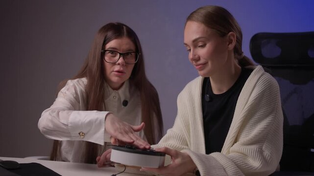 Female designers collaborating on electronic prototypes with soft lighting. Women focused on developing and testing new electronic mockups amid collaborative discussion