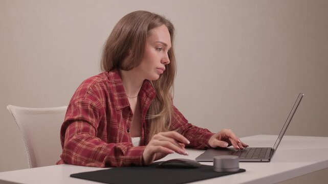 Young lady editing content from home. Female professional concentrating on digital editing task. Young woman in casual attire diligently working on her laptop at home