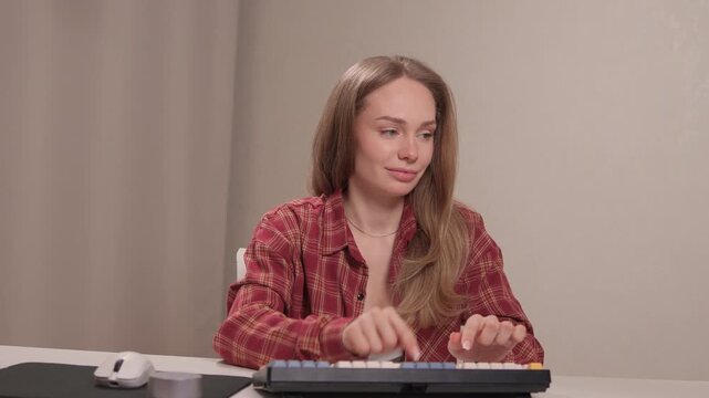 Focused woman typing on keyboard. Woman engaged in remote writing tasks. Female professional diligently performing editing and writing activities with organized workspace