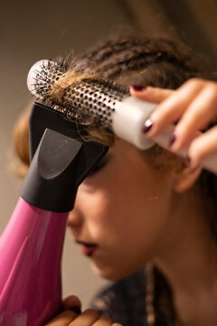 Woman blow drying and styling her hair with brush