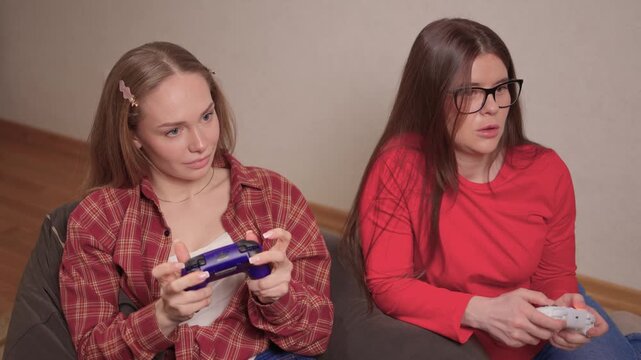 Women play games. Relaxed friends enjoying video games with cheerful interactions. Two women engage in friendly game night amid comfortable surroundings and joyful laughter