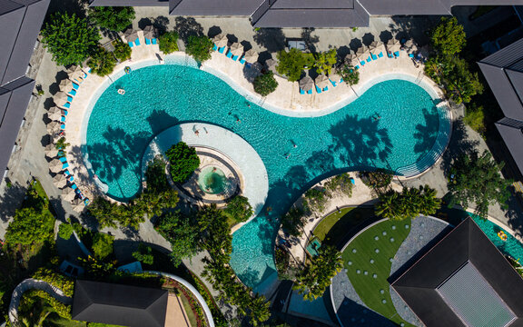 Aerial view of the swimming pool at Marriott's Bali Nusa Dua Gardens with lush tropical landscaping, sun loungers, and palm trees in Kecamatan Kuta Selatan, Bali, Indonesia.