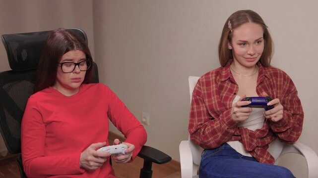 Women play games. Relaxed friends enjoying video games with cheerful interactions. Two women engage in friendly game night amid comfortable surroundings and joyful laughter