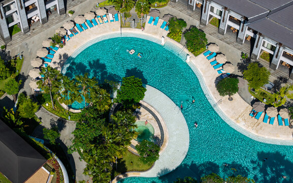 Aerial view of the swimming pool at Marriott's Bali Nusa Dua Gardens surrounded by lush palm trees and sun loungers in Kecamatan Kuta Selatan, Bali, Indonesia.