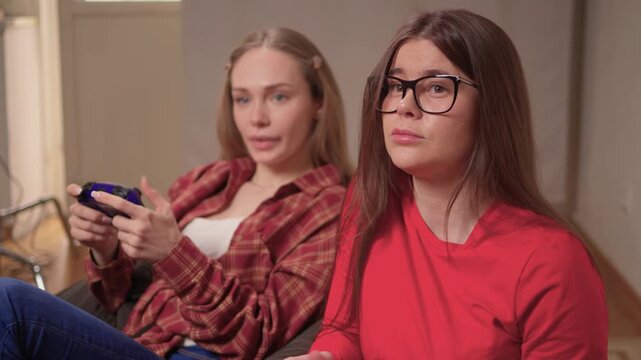 Women play games. Relaxed friends enjoying video games with cheerful interactions. Two women engage in friendly game night amid comfortable surroundings and joyful laughter