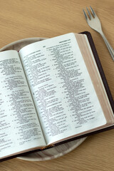 Fototapeta premium Holy bible on a plate. Christian fasting, spiritual food concept.