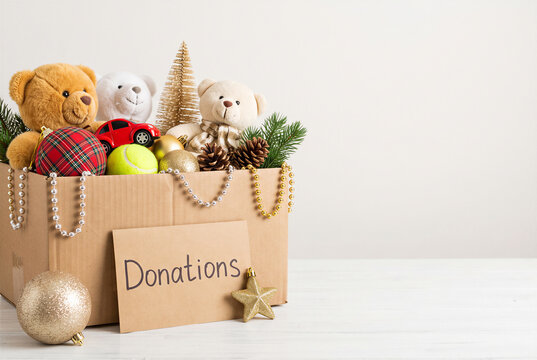 Christmas donation box filled with toys and festive decorations on minimal background with copy space.