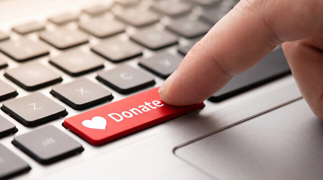 Finger pressing red donate button on laptop keyboard for online charity contribution and digital fundraising concept.