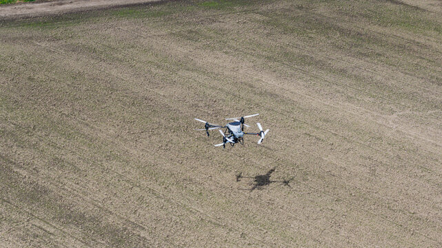 Aerial view of an agricultural drone spraying crops over a large tilled field in Zeewolde, Flevoland, Netherlands.