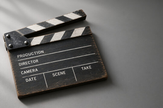 Weathered wooden film clapperboard on grey surface for filmmaking and cinema production concept