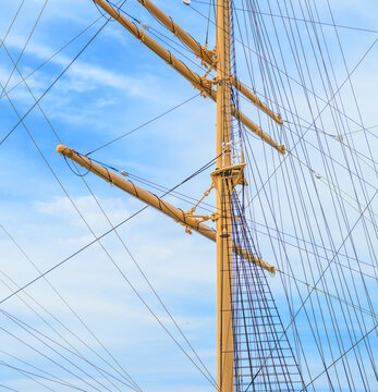 Traditional tall ship mast rigging rising against clear sky.
