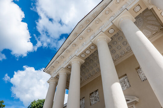 Vilnius Cathedral Basilica facade with classical white columns, ornate ceiling and carved reliefs viewed from below against blue sky in Vilnius, Lithuania