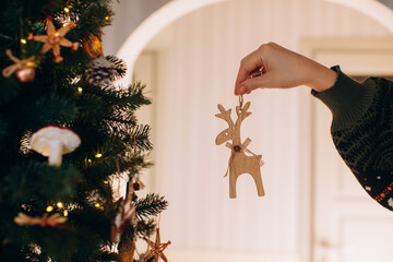 Hand decorating christmas tree with wooden reindeer ornament © Iryna