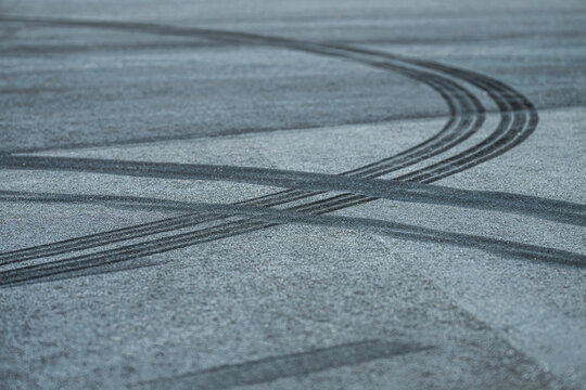 Curving black tire skid marks across textured asphalt surface.
