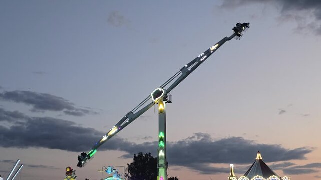 Thrilling amusement park ride spinning high in sky outdoors excitement adrenaline funfair carnival attraction horizontal view entertainment daytime clouds leisure concept video. Video 4k