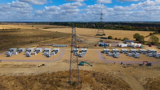 Aerial view of the Eaton Socon Substation featuring a solar farm and battery energy storage systems, with power pylons and construction equipment in St. Neots, England, United Kingdom.