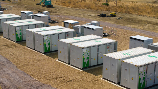 Aerial view of Eaton Socon Substation featuring rows of battery energy storage system containers with green lightning bolt logos on a gravel site in St. Neots, England, United Kingdom.