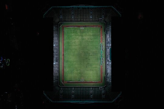 Aerial view of Maguwoharjo Stadium at night with illuminated football pitch and surrounding seating stands in Kecamatan Depok, Daerah Istimewa Yogya, Indonesia.