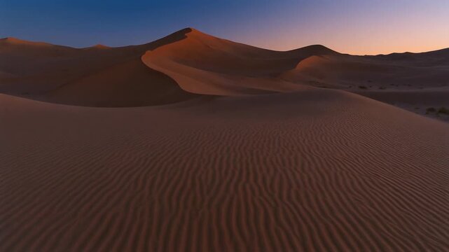 Expansive desert landscape featuring rolling sand dunes sculpted by wind, bathed in the warm glow of the setting sun creating dramatic shadows and a sense of serene, vast emptiness under