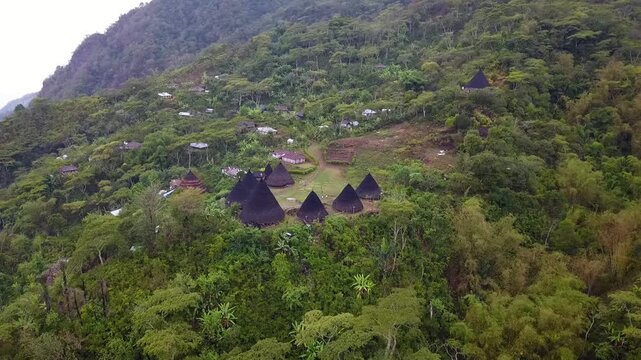 Cinematic drone flight over mist covered mountains surrounding Wae Rebo traditional site