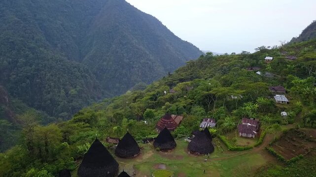 Slow tracking drone video of morning fog drifting over Mbaru Niang huts in Wae Rebo