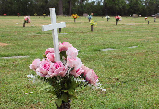 Cross and Bouquet of Pink Roses on Headstone in Rural Cemetery