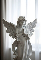 Obraz premium Spirituality and faith concept white angel statue with praying hands for religious peace hope and divine protection in a soft light indoor setting