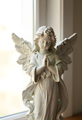 Obraz premium Spirituality and peace praying angel statue with folded hands for religious comfort hope and divine guidance in a serene home interior setting