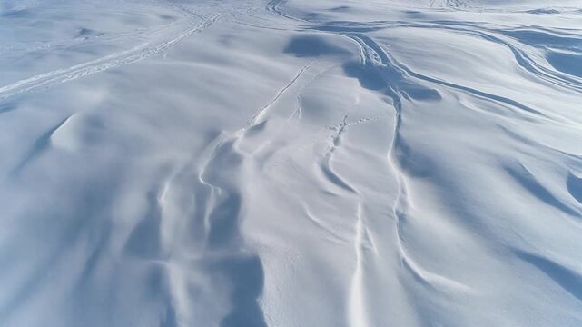 Capturing the stark beauty of wind-sculpted snow formations under a vast, clear sky, revealing the subtle textures and flowing patterns created by natural forces in a serene winter landscape