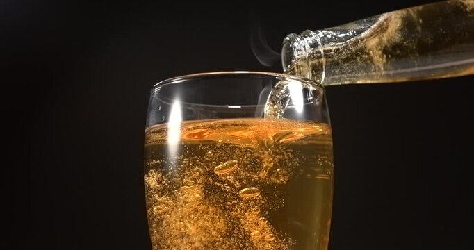 Beer pouring from glass bottle into mug in slow motion