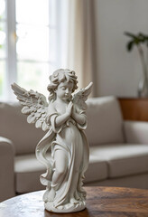Obraz premium Spirituality and peace, small angel statue with praying hands for religious home decor and meditation, serene cherub figurine on a wooden table in living room
