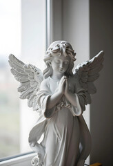 Obraz premium Spirituality and faith concept stone angel statue with hands in prayer position for religious peace hope and comfort in a quiet indoor setting